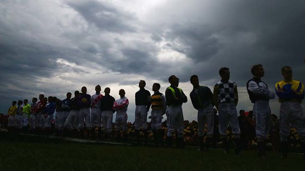Jockeys line up before the Melbourne Cup as the clouds gather over Flemington.