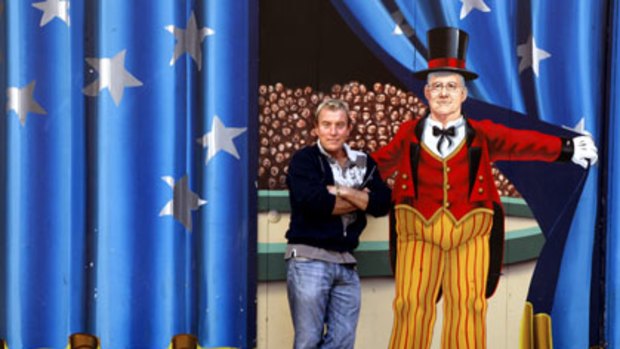 Show time ... Ashley Taylor, the resident artist at Luna Park since 2003, with one of his colourful works.