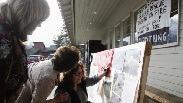 Brenda Neal, right, looks at aerial photos of the landslide for her missing husband's car.