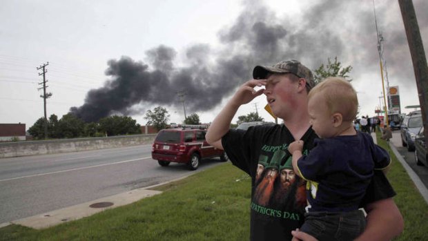 Mark Paugh carries his 15-month-old son Ryan as they watch smoke from a train derailment in White Marsh, Maryland.
