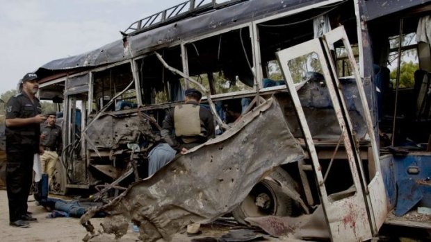 Terrorist target: Investigators examine the police bus destroyed in yesterday's deadly attack in Karachi.