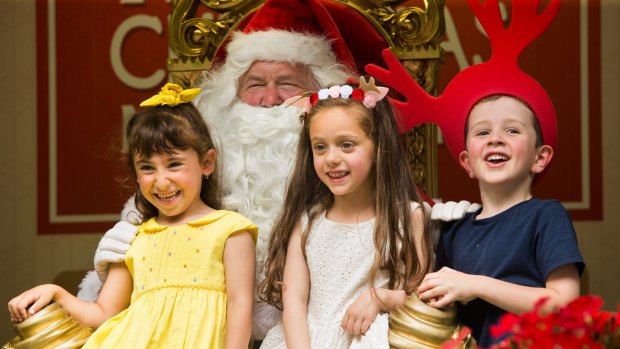 Tough but fun: Santa hard at work in the heat in the City Square with (left to right) Isabella Meddis, Simae Cutrupi and Patrick Creane.