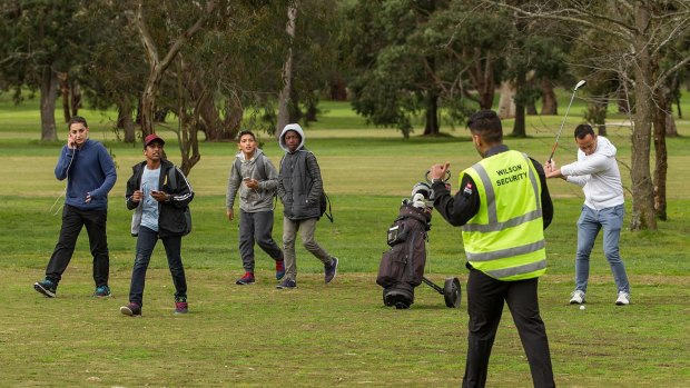A security guard removes Pokemon Go gamers while a golfer hits his ball on the Glen Waverley Golf Course.