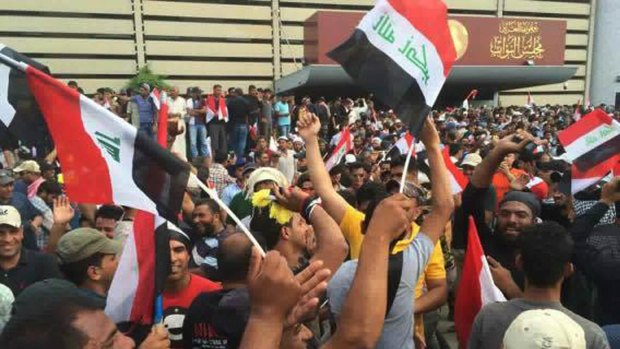 Protesters raise the Iraqi flag outside parliament in Baghdad's Green Zone.