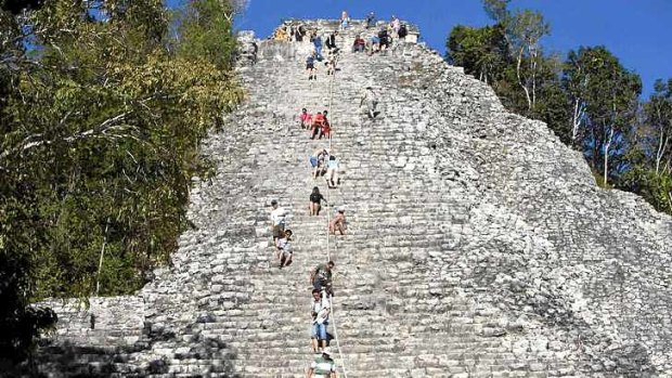 Tourists climb the Maya pyramid of Nohoch Mul at the archaeological site of Coba.