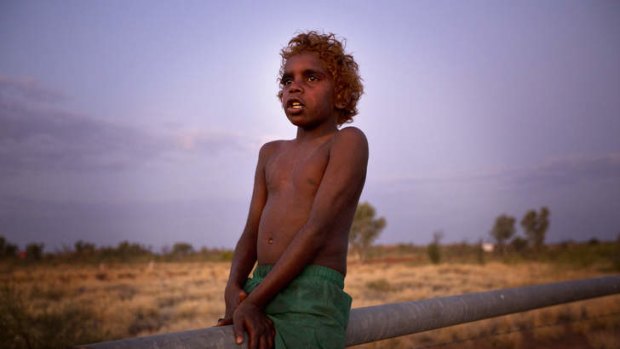 Stanley Waistcoat, 8, plays at dusk by his Grandmother's 'humpy' bush house, by the Stuart Highway just north of Tennant Creek, Northern Territory. His grandmother left town and built the 'humpy house' a few months ago to get away from troubles exacerbated by overcrowded houses. Tennant Creek is currently in a housing crisis.