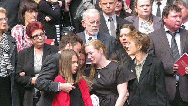 Members of Ken Talbot's family comfort one another at his funeral in Brisbane today.