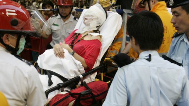 A victim, her head covered in bandages, is carried on a gurney to an ambulance in Mongkok district, a tourist shopping spot in Hong Kong.