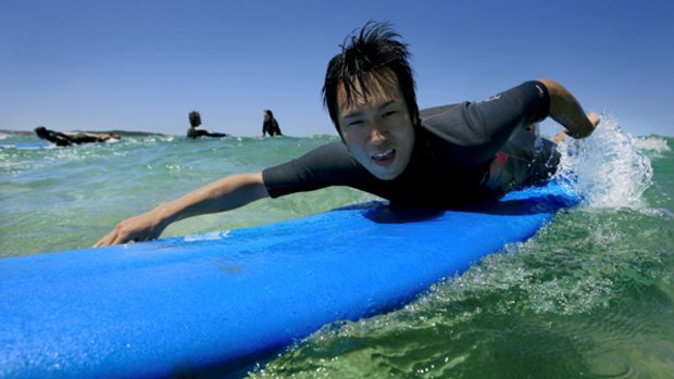 All aboard for fun in Australia ... Hiroshi Kawano, a Japanese tourist, learns to surf at Kurnell peninsula.