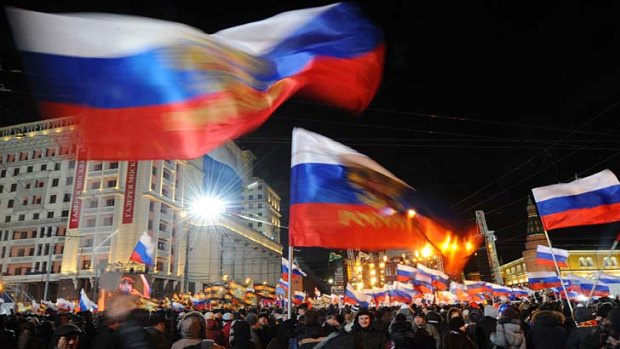 Celebrating victory ... Supporters of Vladimir Putin wave national flags.