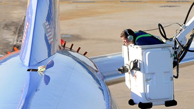 An investigator examines the hole on top of a Southwest Airlines plane.