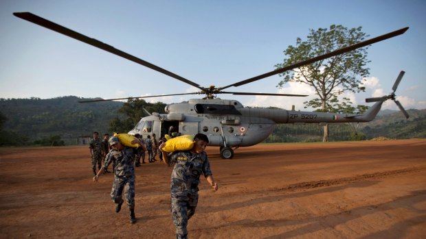 Nepali security personnel carry relief material from an Indian Air Force helicopter in Dhading, Nepal.