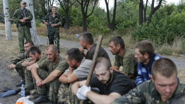 Prisoners-of-war, who are Ukrainian servicemen captured by pro-Russian separatists, sit on the ground as they are assigned to clean a street in Snizhne, Donetsk region.