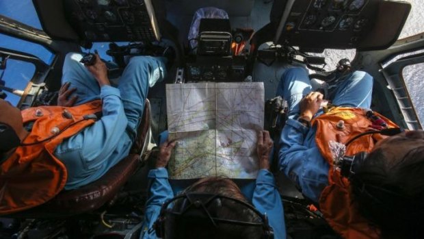 Military personnel work within the cockpit of a helicopter belonging to the Vietnamese airforce as they search for the Malaysia Airlines Boeing 777-200ER jetliner.