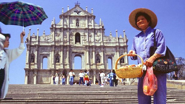 City backdrop ... a Macau vendor offerswares near the facade of St Paul's cathedral.