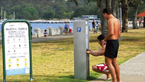 Playing it safe ... beachgoers using the meters at Balmoral Beach. Some residents are forgetting to collect and display their free parking tickets.