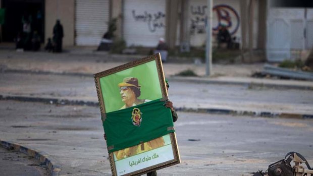 A soldier carries a portrait of Colonel Gaddafi in Misrata during a trip organised by Libyan authorities.