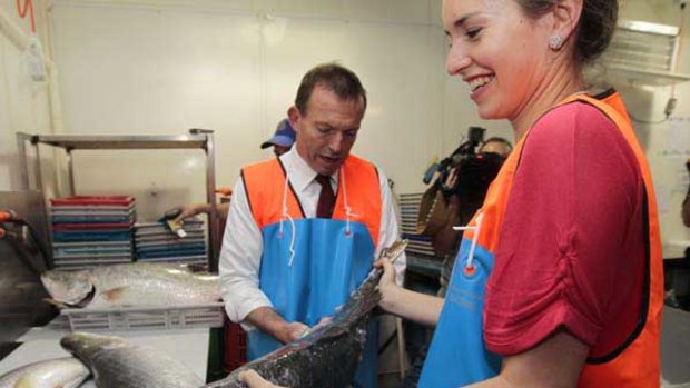 Tony Abbott and daughter Louise fillet a fish at the Mackay Fish Market.