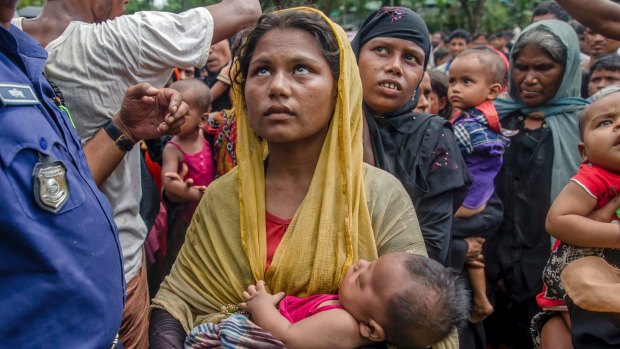 Rohingya Muslim women, who crossed over from Myanmar into Bangladesh, hold their children as they wait to receive aid near Balukhali refugee camp,.