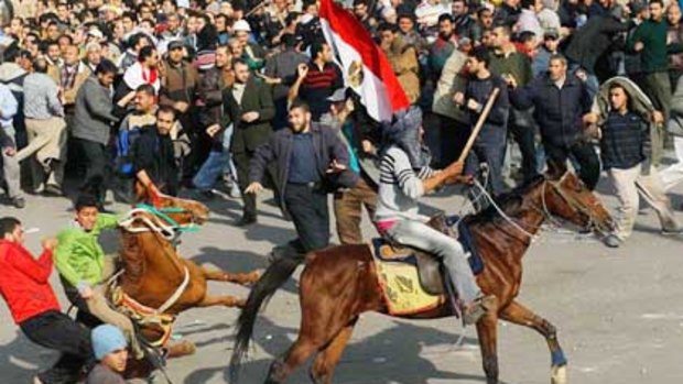 Supporters of Hosni Mubarak ride horses through the melee during a clash with protesters in Tahrir Square, Cairo.
