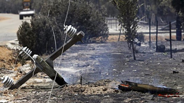 A burnt down power pole sits on the side of the road after a bushfire tore through Toodyay.