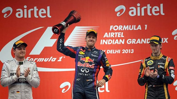 Red Bull driver Sebastian Vettel of Germany holds his trophy aloft after winning the Indian GP and, with it, the world championship. Mercedes driver Nico Rosberg of Germany (left) finished second and Lotus driver Romain Grosjean of France (right) third.