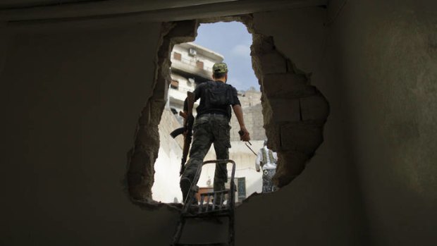 A Free Syria Army rebel walks through a hole in the wall in the neighbourhood of Askar.
