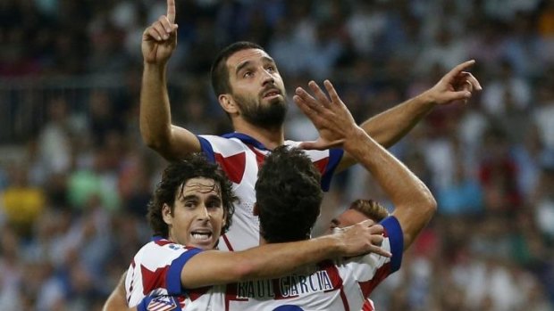 Arda Turan (C) celebrates the winning goal for Atletico Madrid with teammates Tiago (L) and Raul Garcia.