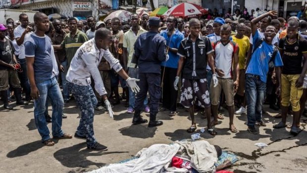 Residents call attention to a man lying dead on a busy street in Monrovia, Liberia.
