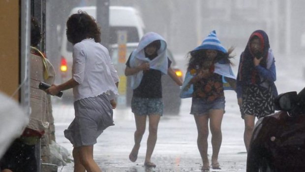 Women walk in strong winds caused by typhoon Neoguri in Naha, on Japan's southern island of Okinawa on Tuesday.