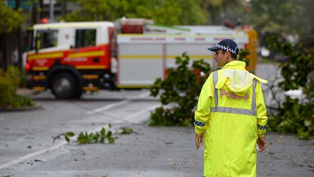 Cyclone clean-up starts: A policeman stands guard to keep onlookers away from fallen powerlines laying across a street.