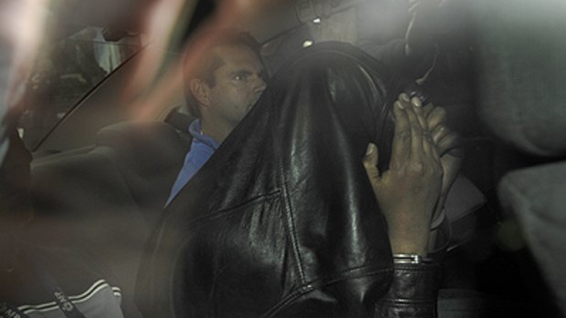 In custody ... a suspect hides his face as he is taken to Melbourne Magistrate’s Court yesterday.