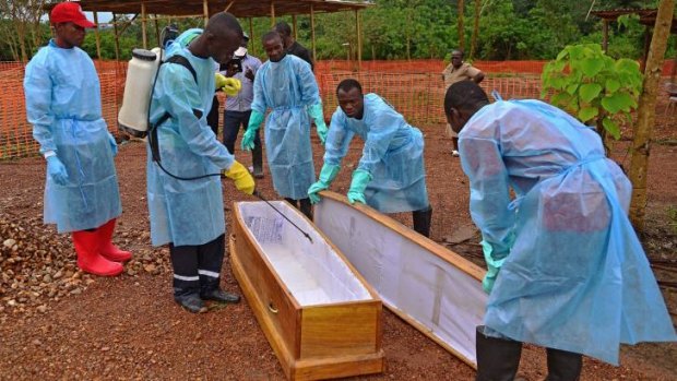 A Sierra Leone government burial team disinfects a coffin at the Medecins Sans Frontieres facility in Kailahun.