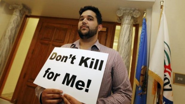 Hossein Dabiri with Oklahoma Coalition Against the Death Penalty holds a sign protesting the death penalty at the State Capitol in Oklahoma City.