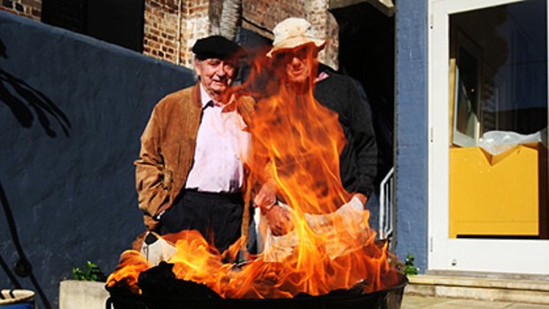 Charles Blackman and Robert Dickerson watch as three paintings falsely ascribed to them go up in smoke yesterday.