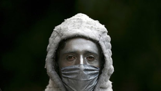 A street performer wears a mask painted silver in Mexico City.