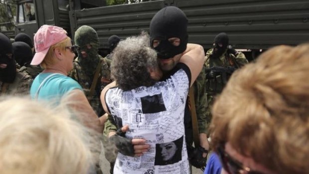 A woman embraces separatist fighters as they parade on the streets of Donetsk near Lenin Square on the day of the Ukrainian Presidential elections. Donetsk, East Ukraine.
