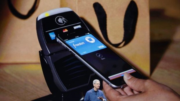An Apple iPhone making a tap and go transaction behind CEO Tim Cook.