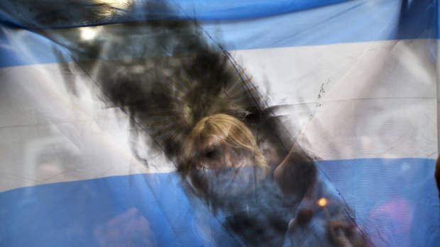 A woman holds up an Argentine flag smeared with black paint as people gather near the funeral home where a private wake was held for Alberto Nisman.