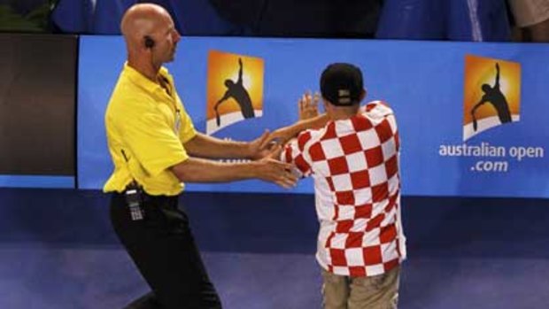 An Australian Open security guard apprehends a man who invaded centre court last night.