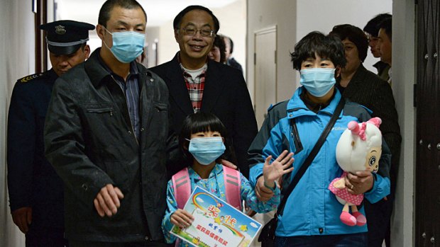 A seven-year-old girl who had Beijing's first human case of H7N9 bird flu with her parents as she prepares to go home from Ditan hospital in Beijing on April 17.