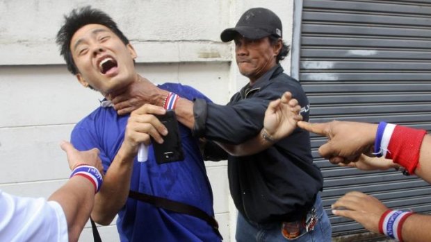 Anti-government protesters attack a voter near a polling station in Bangkok.