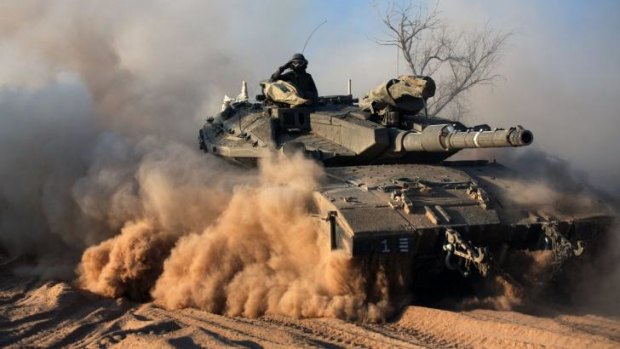 An Israeli soldier salutes on a Merkava tank, as part of the Israeli army deployment near Israel's border with the Gaza Strip.