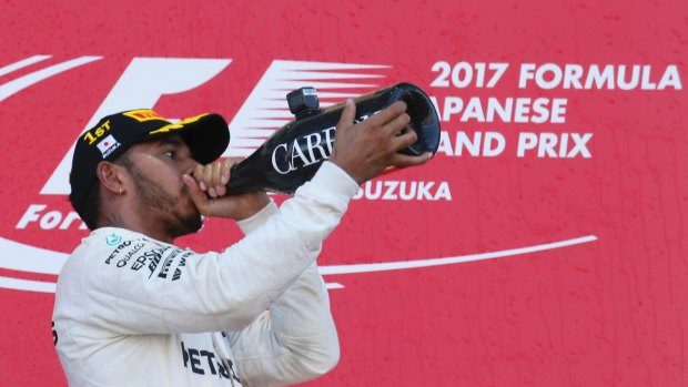 Mercedes driver Lewis Hamilton of Britain drinks a bottle of champagne on the podium after winning the Japanese Formula One Grand Prix at Suzuka Circuit in Suzuka, central Japan, Sunday, Oct. 8, 2017. (AP Photo/Toru Takahashi)