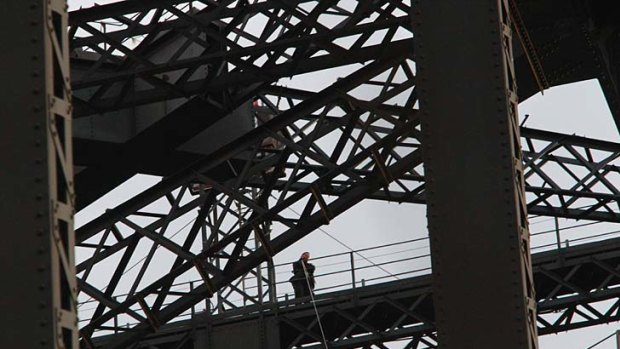 The protester speaks on his mobile phone after unfurling banners on the Sydney Harbour Bridge.