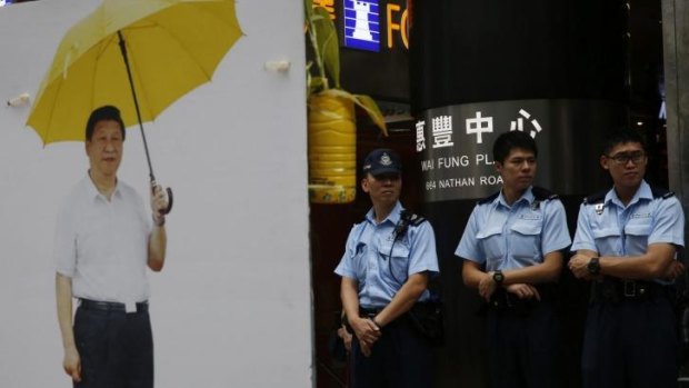 Protest symbol: Police officers stand guard next to a picture of Chinese President Xi Jinping holding a yellow umbrella, the symbol of the pro-democracy protest, in the occupied area of the Mong Kok district of Hong Kong.