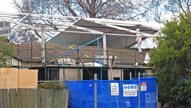 Workers wrap a plastic shield over a house in Downer for the safe removal of asbestos last year.