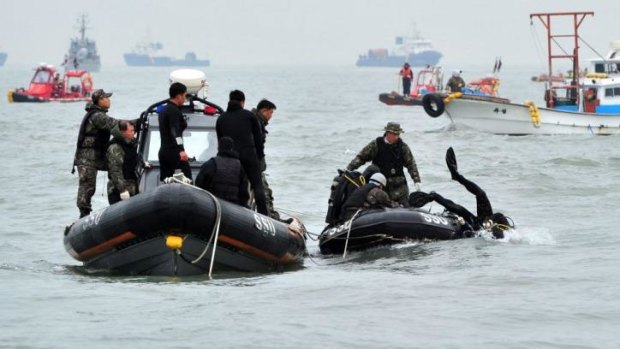 A navy diver enters the waters to search for passengers from the capsized ferry.