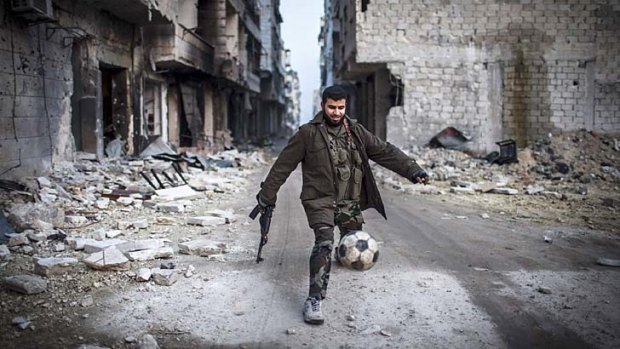 A game amid war ... a rebel plays football in the shattered suburb of Saif-al-Dawla in Aleppo on Wednesday.