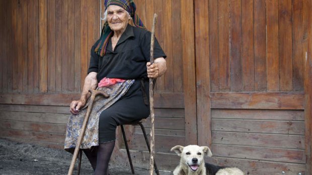 Peasant woman sitting on road with dog in Georgia.